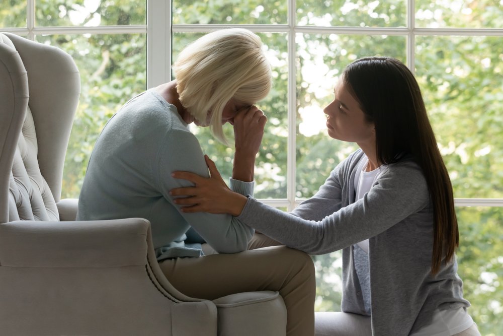 Woman comforting a grieving family member seated by a window, illustrating the emotional impact on families pursuing a wrongful death claim