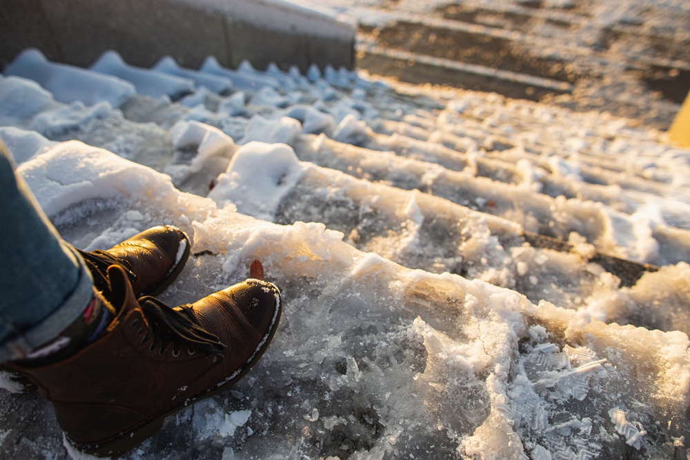 Person standing on icy, unshoveled steps, a common cause of snow and ice removal liability claims in New Jersey