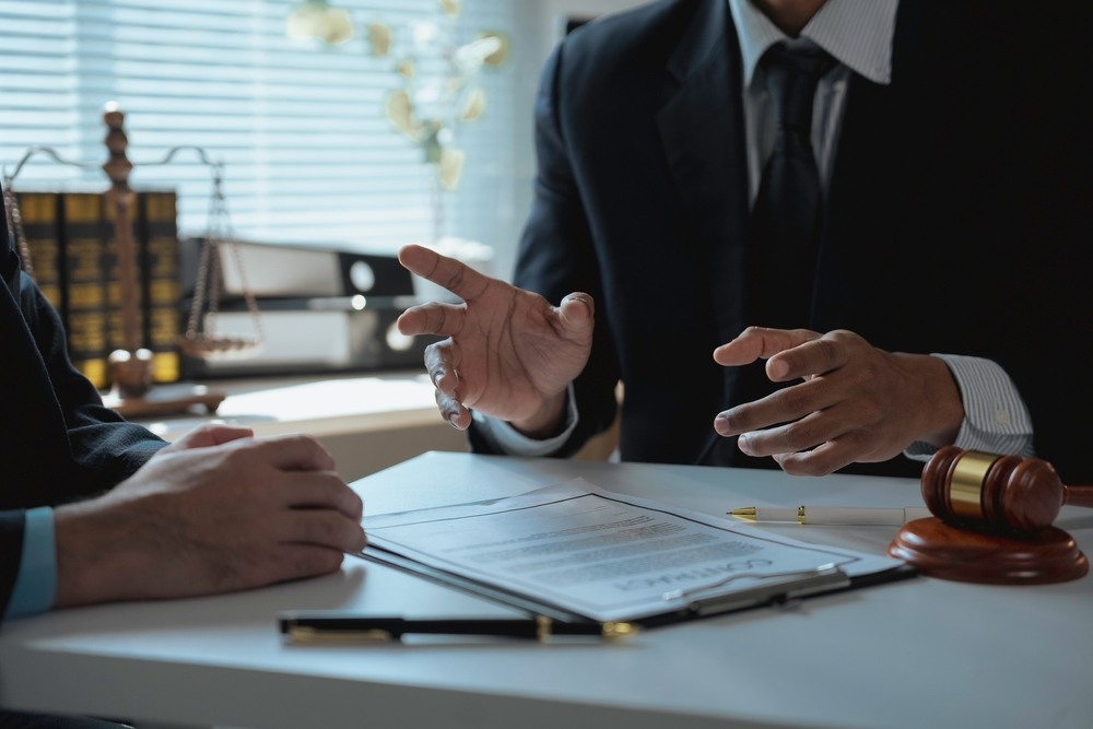 Attorney explaining case details to a client at a desk with a contract and gavel visible, representing personal injury legal consultation