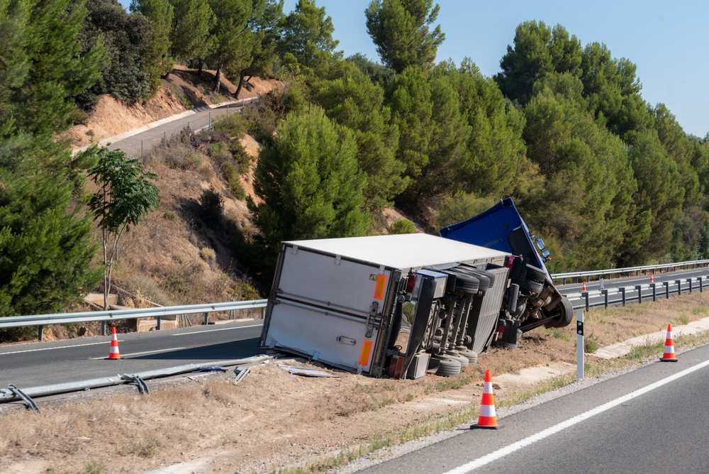 Overturned box truck resting on a highway shoulder after a crash, illustrating the severity of commercial truck accidents in New Jersey