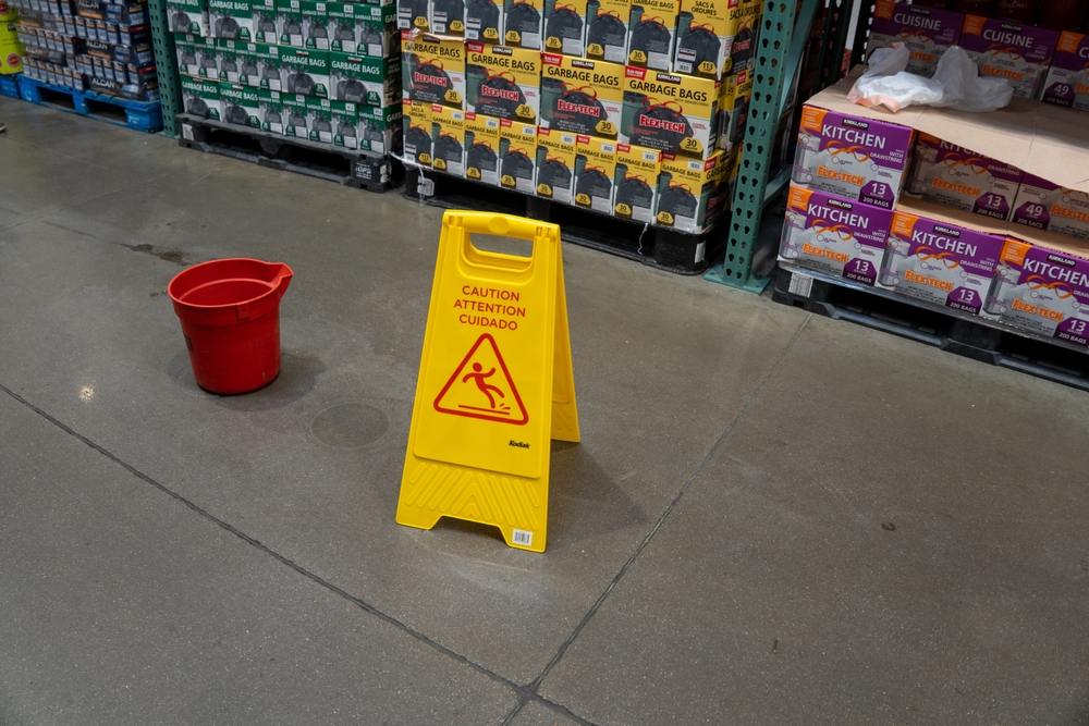 Yellow caution wet floor sign placed in a warehouse store aisle near shelved products