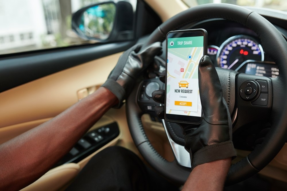 Rideshare driver accepting a new trip request on phone mounted to steering wheel, illustrating driver app status relevant to Newark Uber accident liability